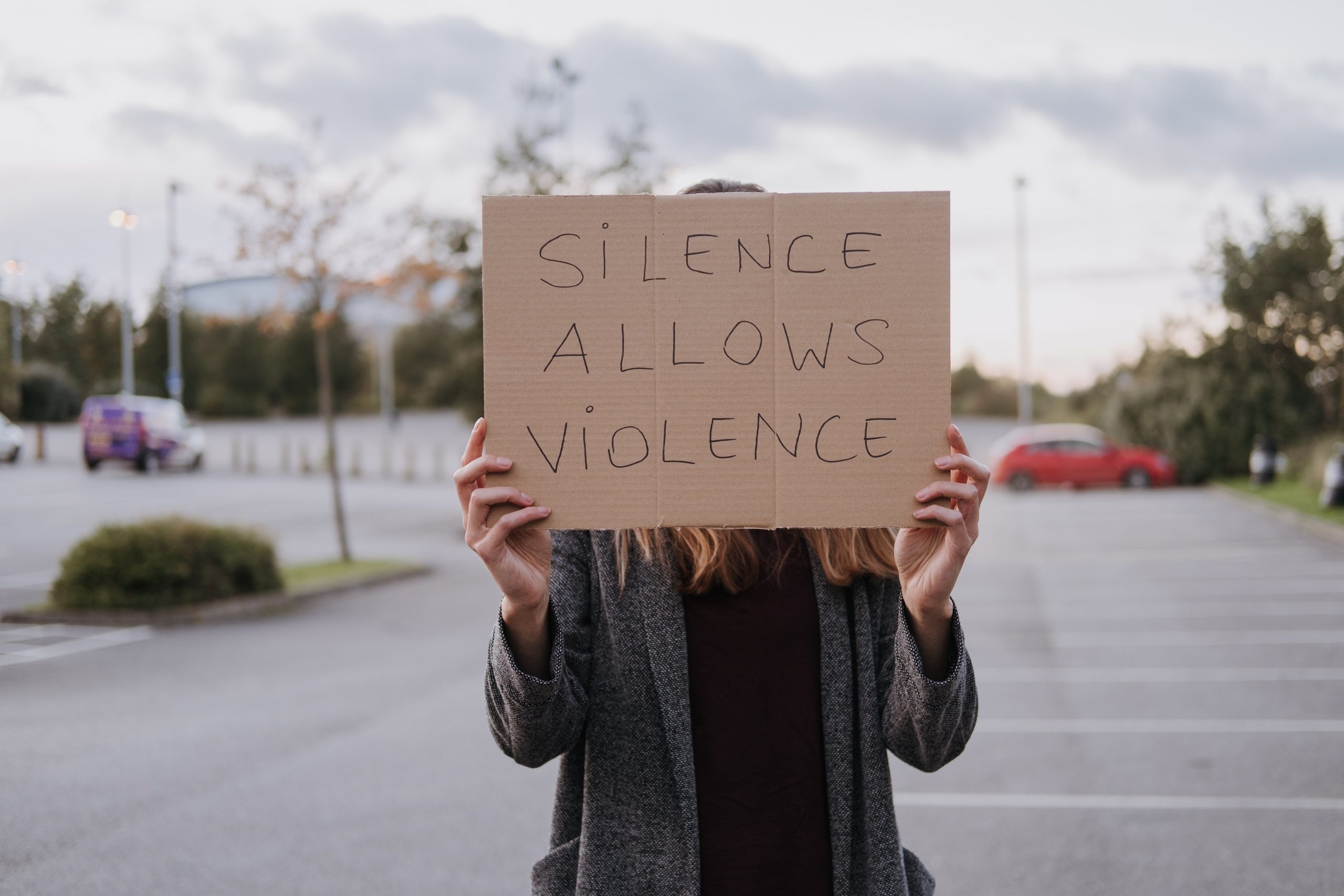 A person holds a sign saying 'silence is violence'