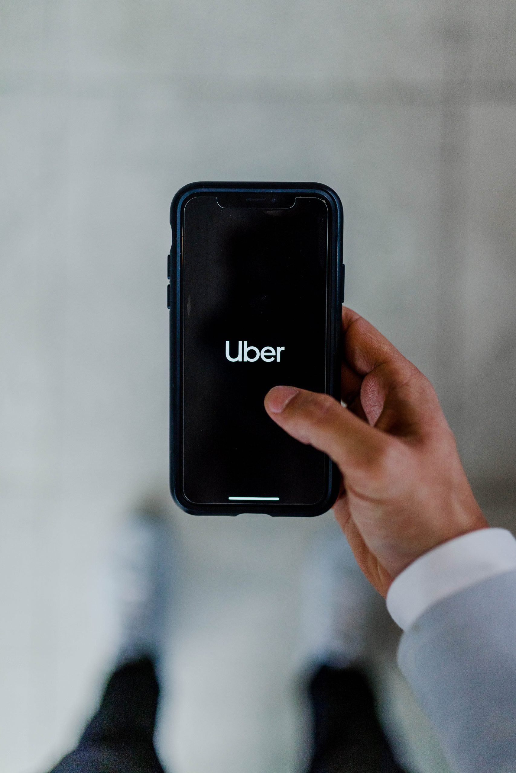 A smartphone screen shows the Uber logo 