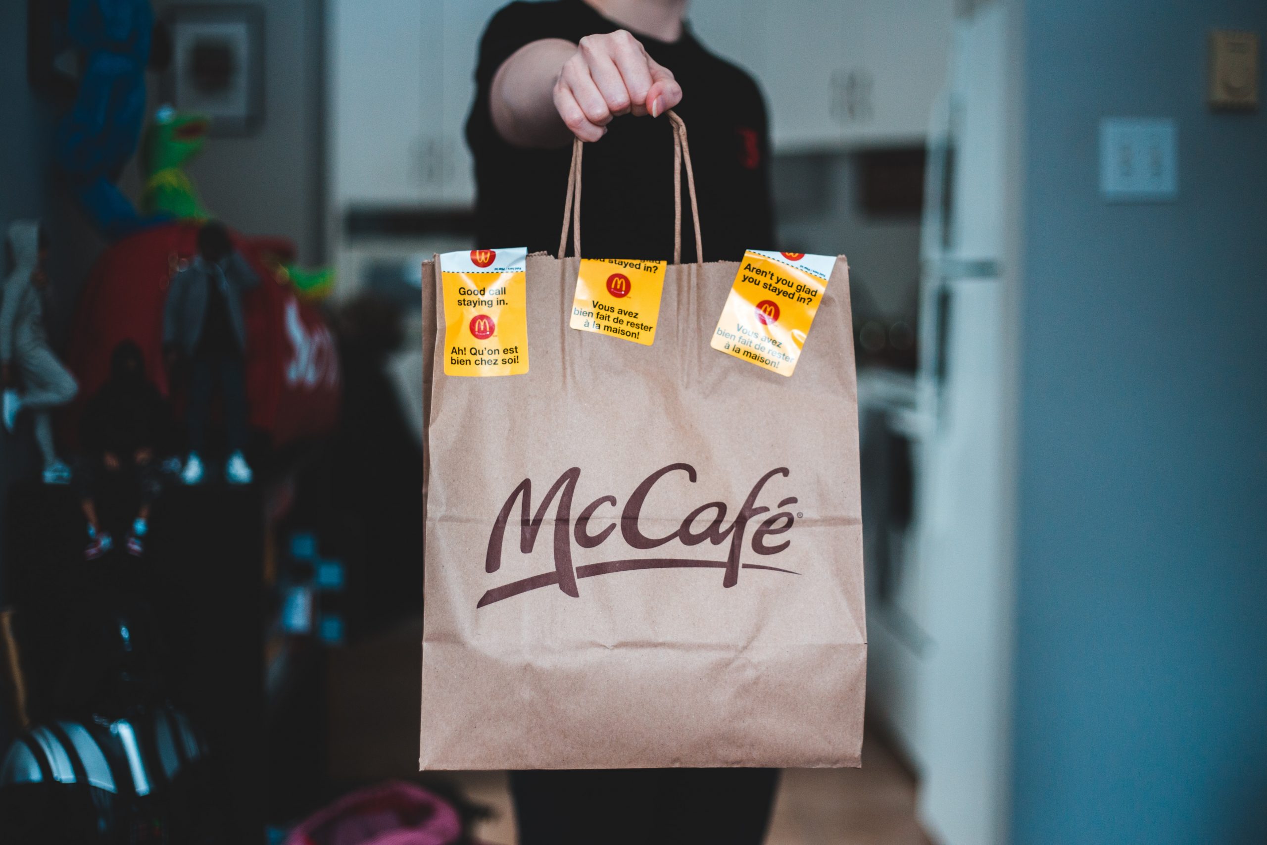 A "McCafe" paper bag is held up to the camera