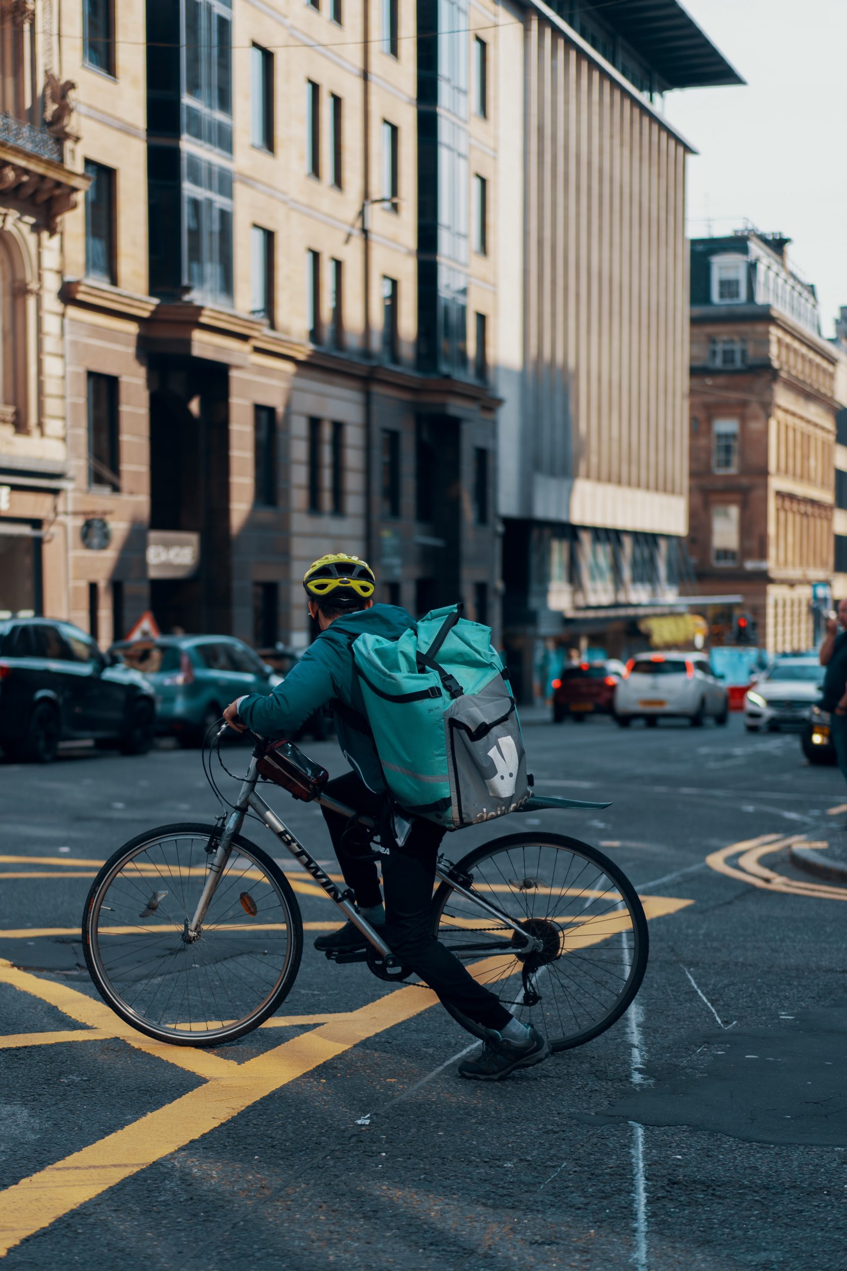 A deliveroo driver riding a bike crosses a road in Glasgow