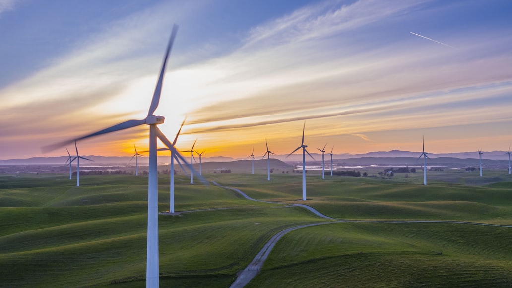 A windfarm amid hills at sunset
