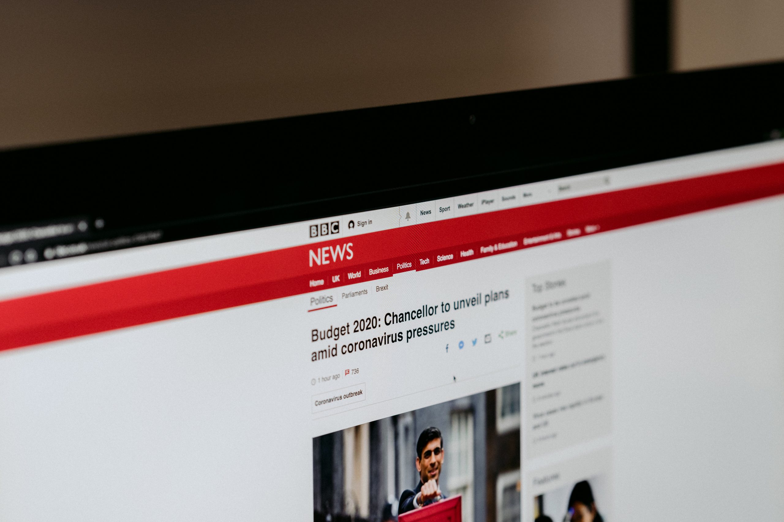 A photo shows a laptop screen with a news story on the BBC website. The headline is highlighting the release of the budge amidst the pandemic