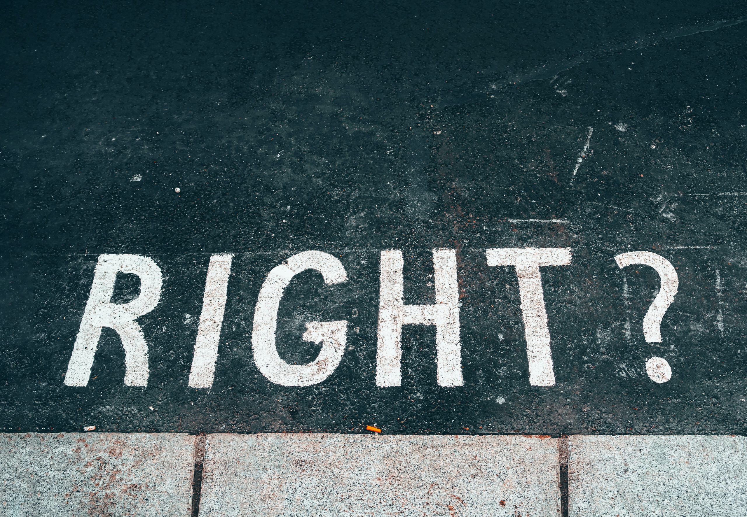 White text in capital letters reads "right?" on a black pavement.