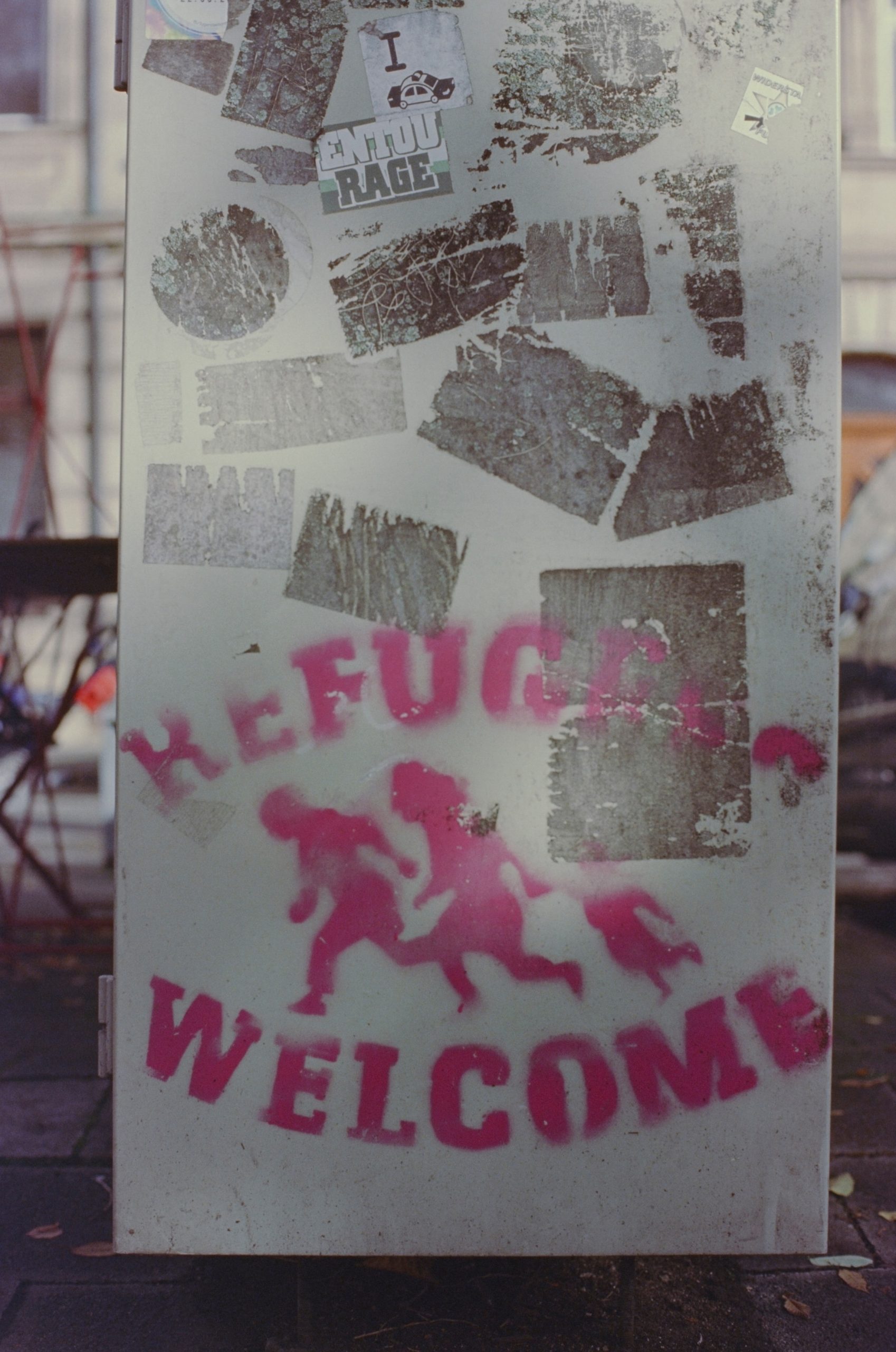 Graffiti reads "refugees welcome" in pink ink