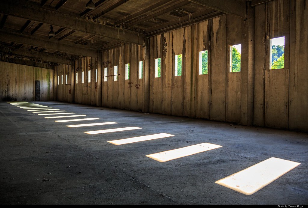 The inside of a camp shows barren flooring and tiny slit windows of a delapidated old building