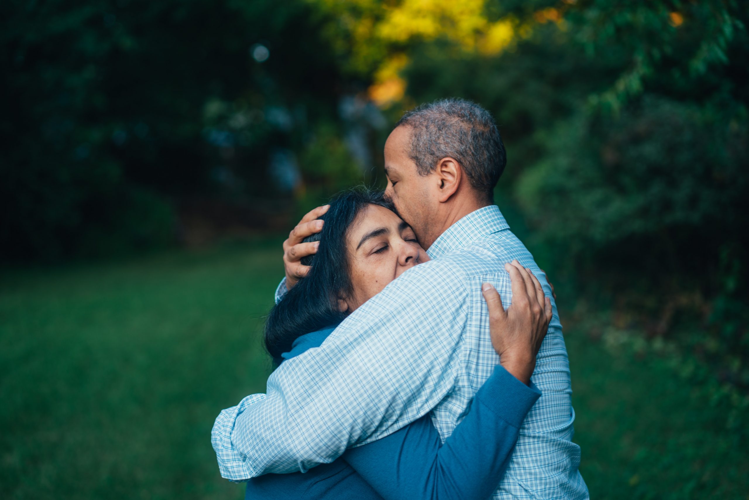 A middle aged Black couple embrace in a garden