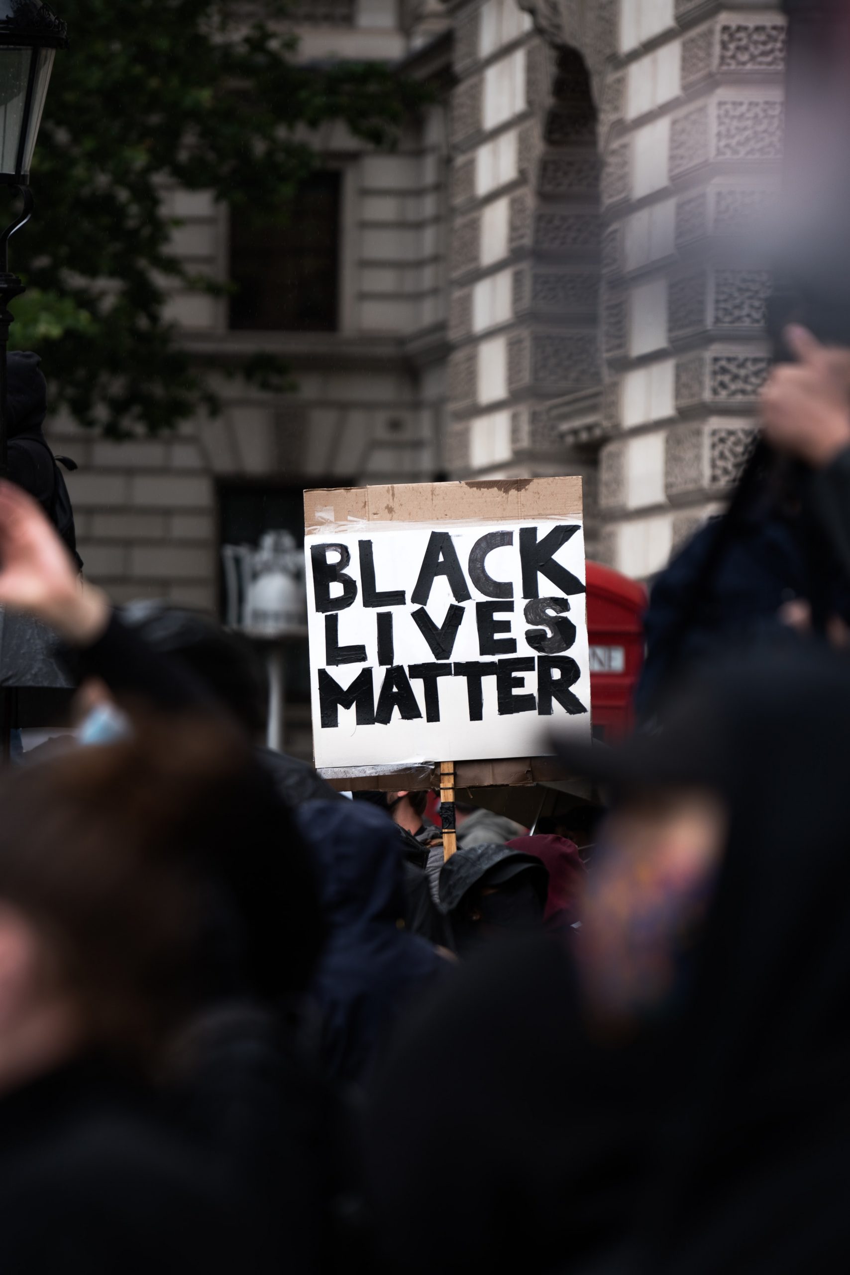 A sign reads "Black Lives Matter" on white card amidst a crowd