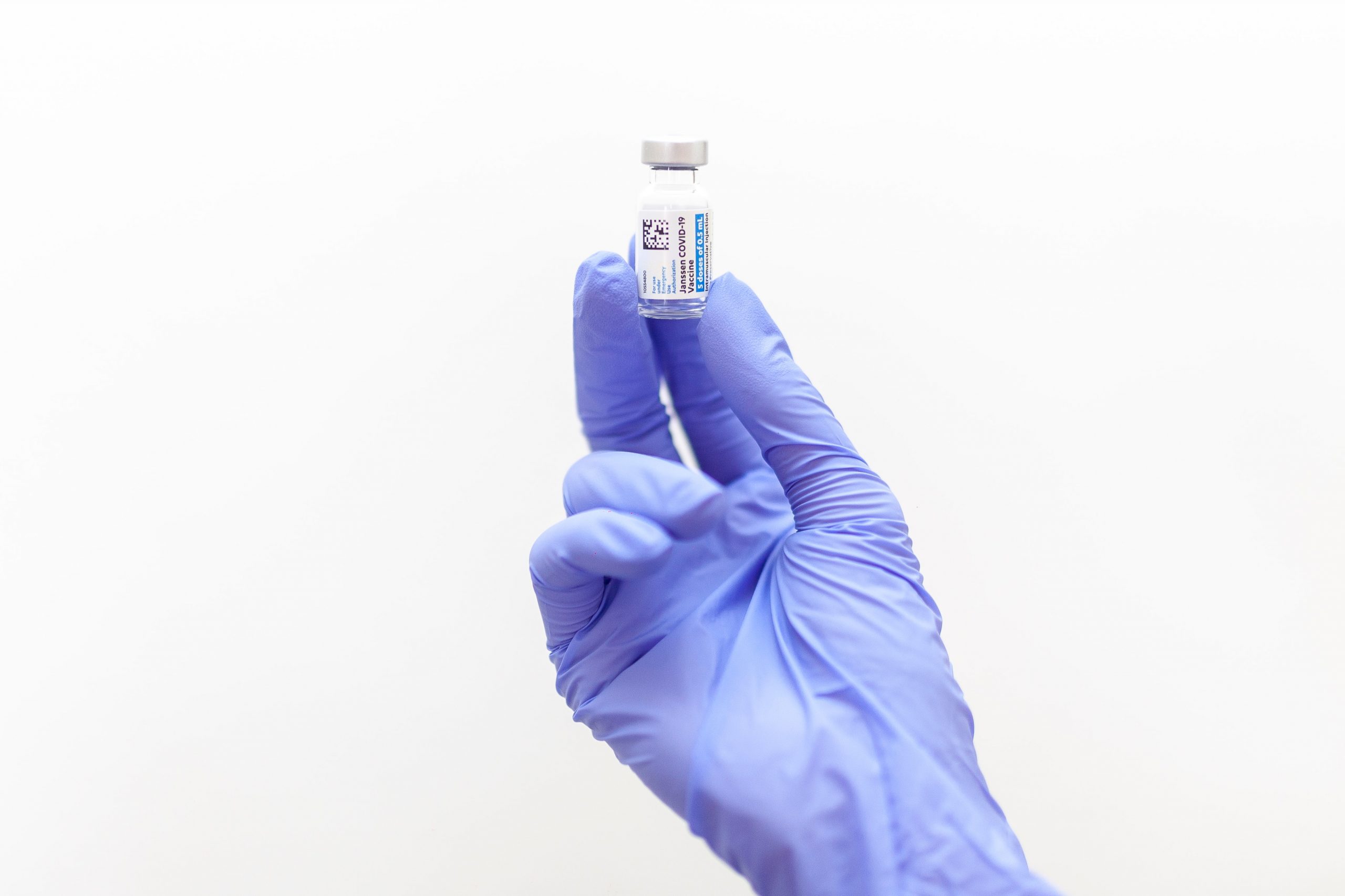 A globed hand holds a vial of Covid-19 vaccination 