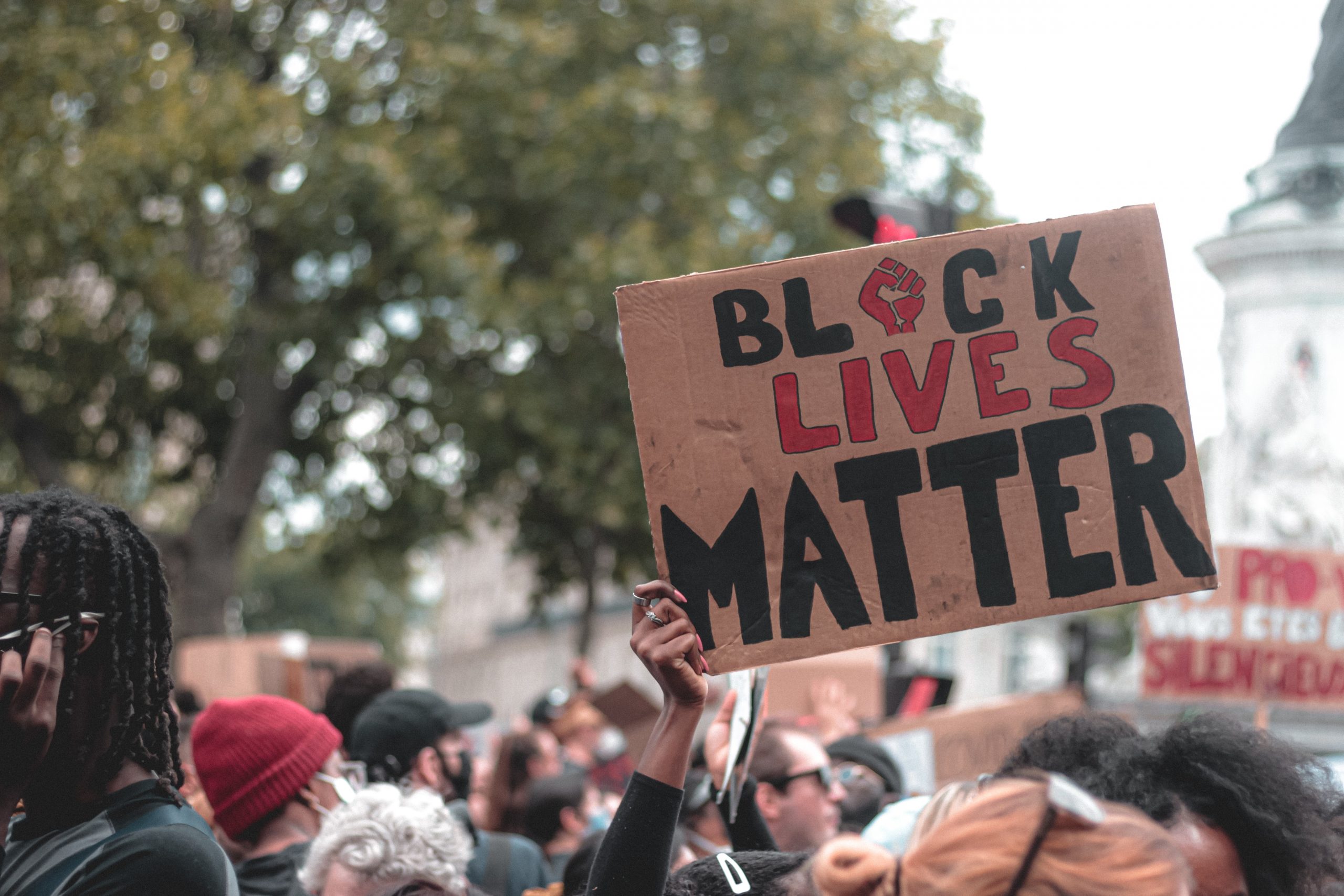 A sign reads "black lives matter" above a crowd of protesters