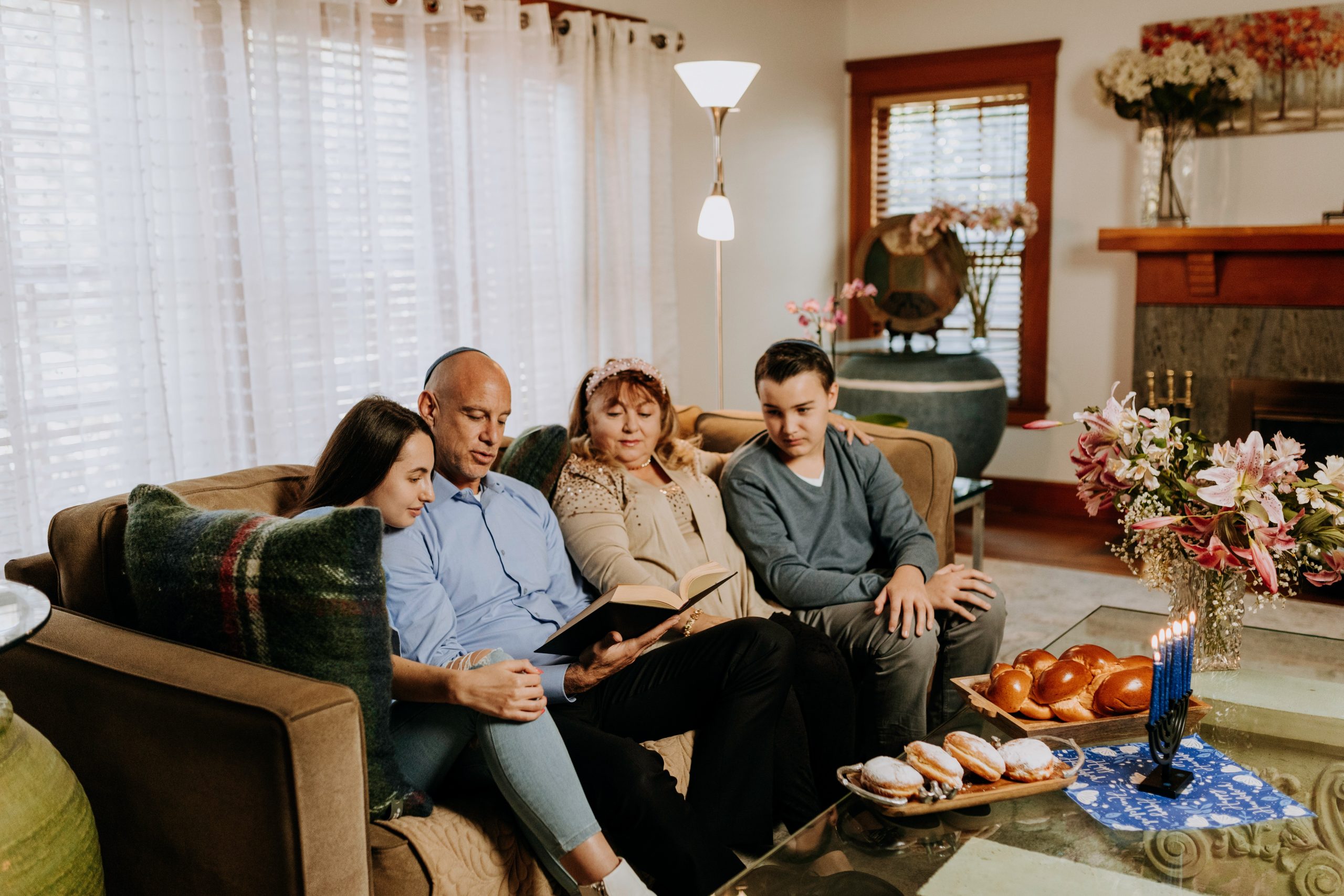 A Jewish family gather around a copy of the Torah on a sofa.