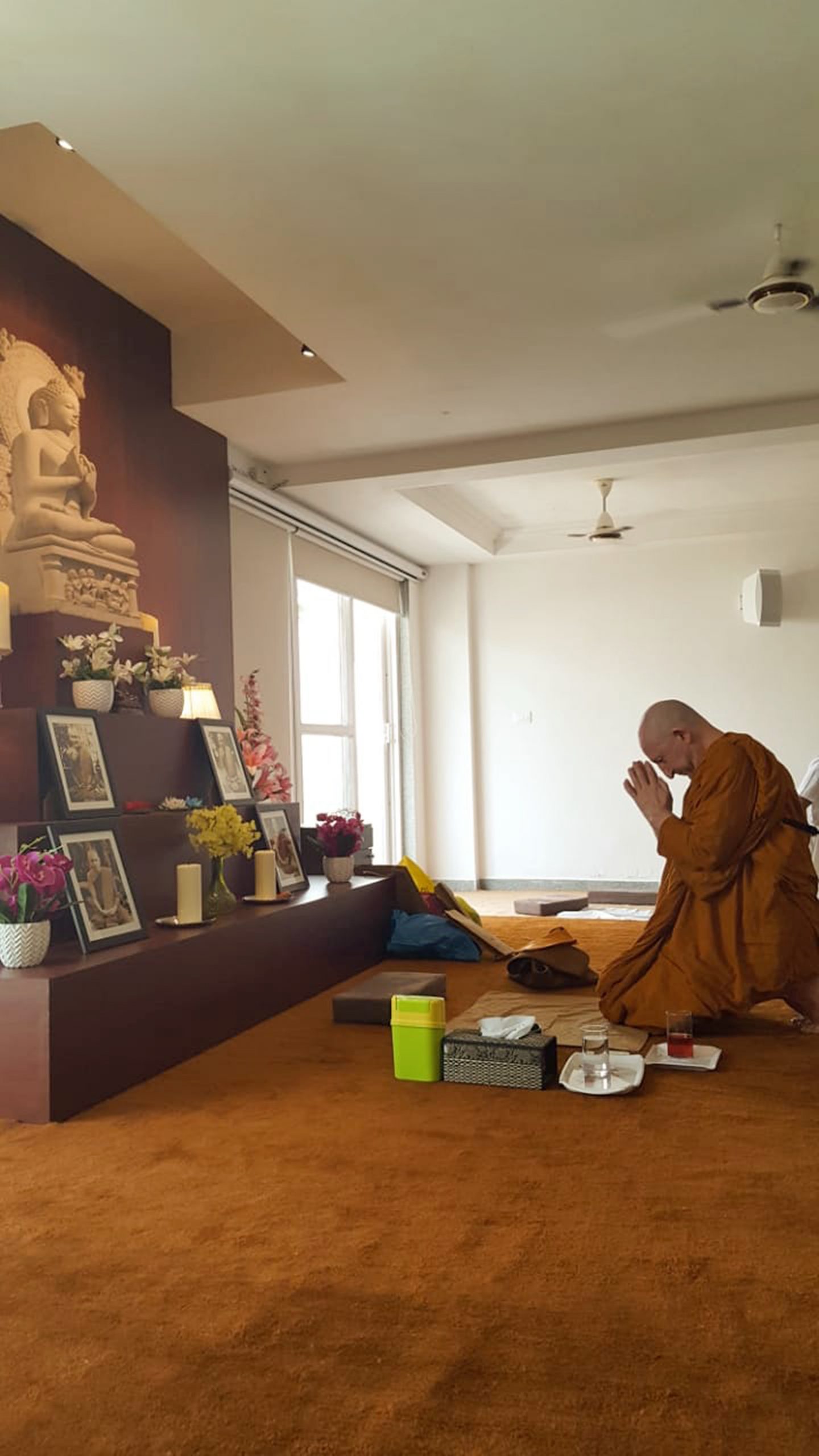A Buddhist man prays on his knees in front of an altar
