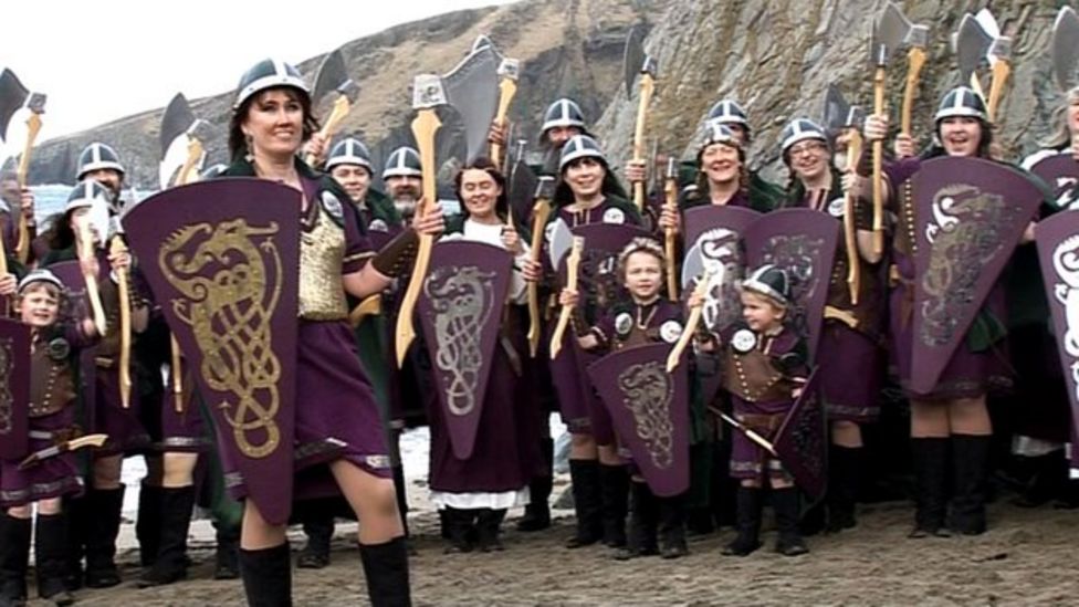 A group of women and girls stand in a crowd dressed as vikings