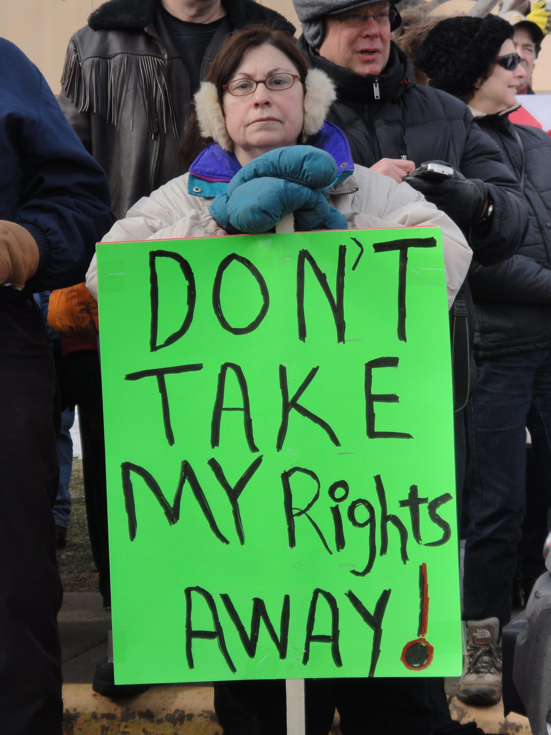 A woman at a demo leans on a placard which reads 'Don't take my rights away'