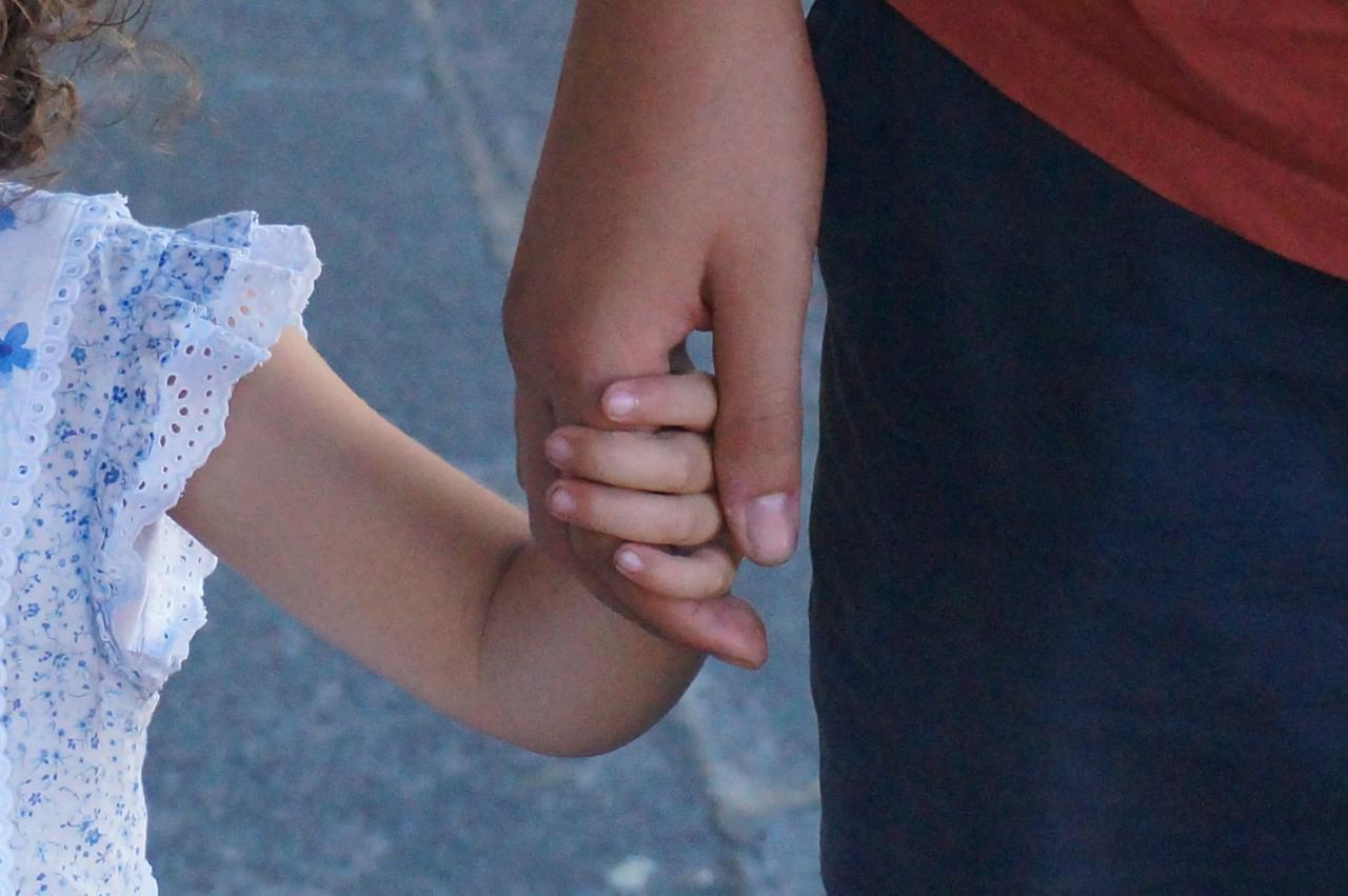 A child holds hands with an adult