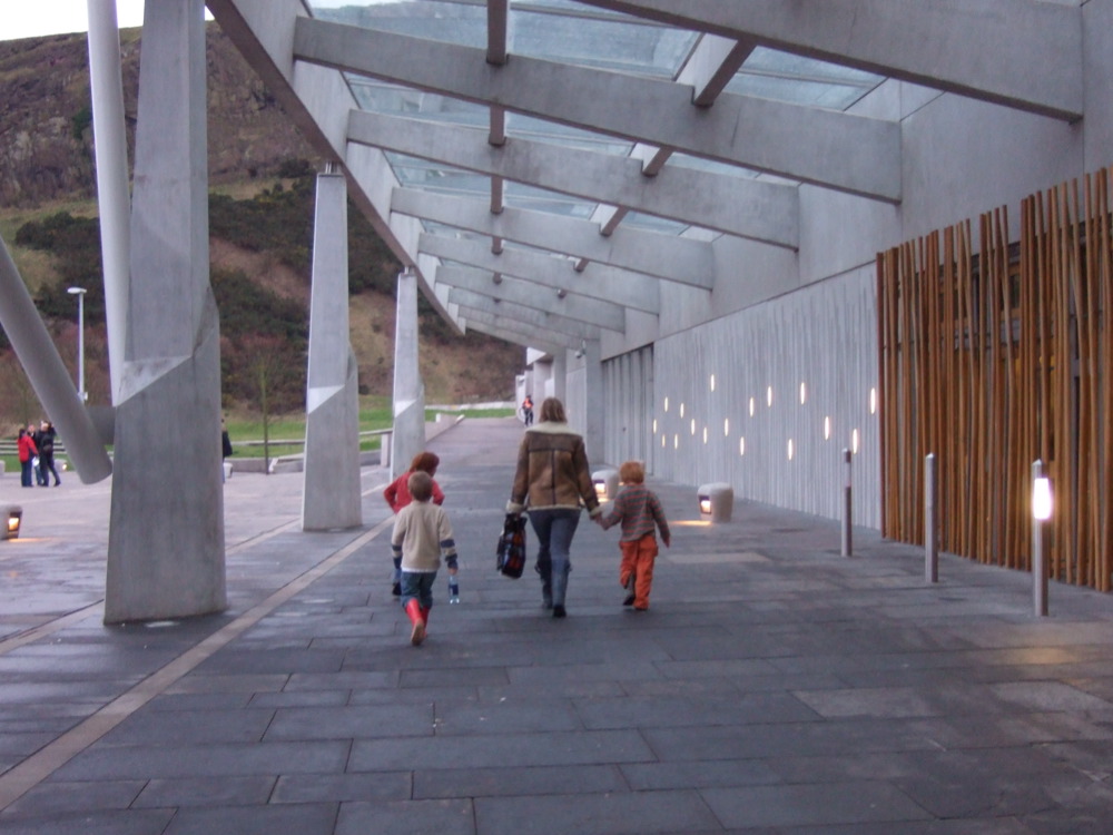 A women and two children walk outside the Scottish Assembly.