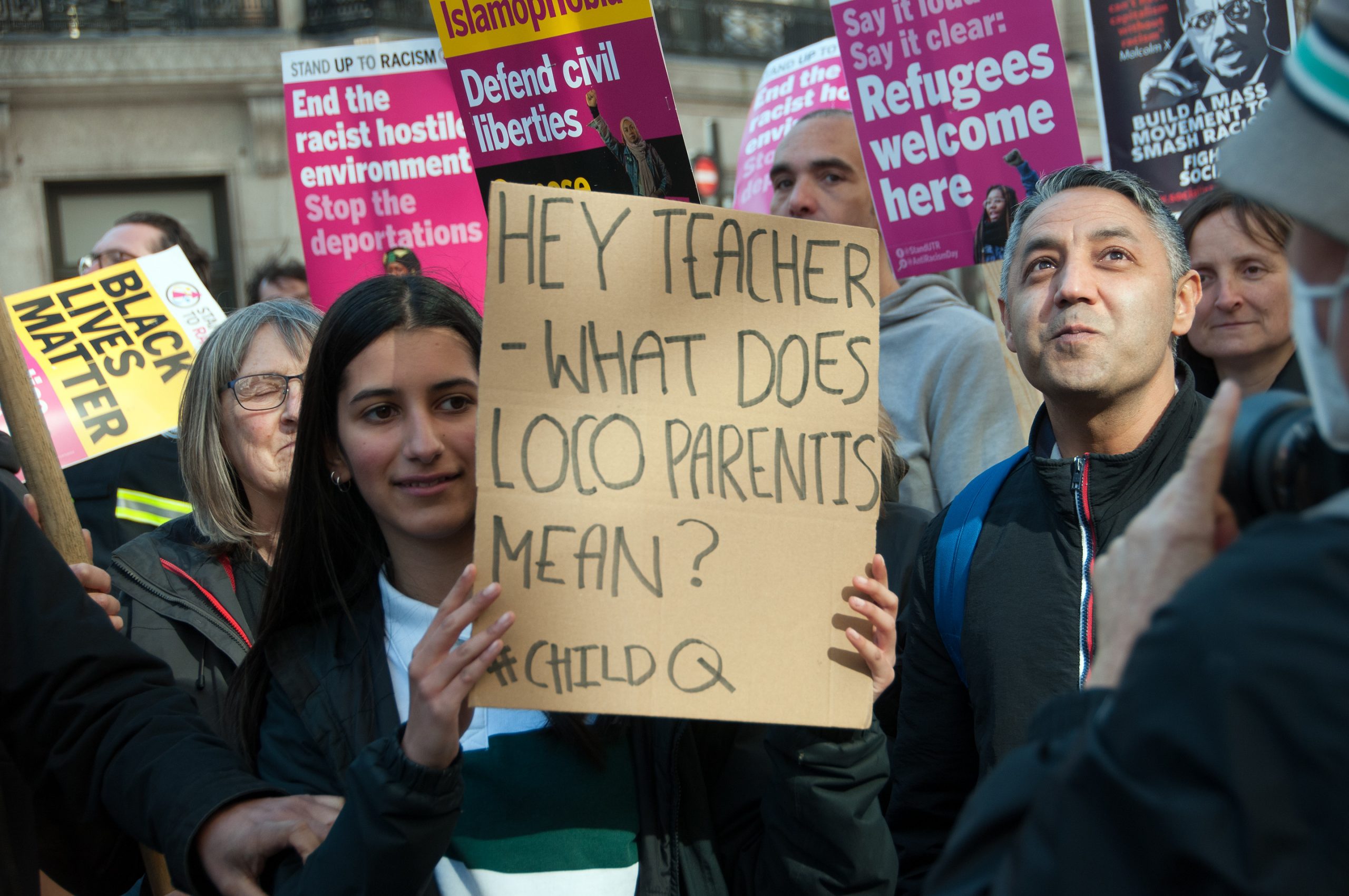 A sign at a protest reads: "Hey Teacher- what does Loco Parentis mean? #ChildQ