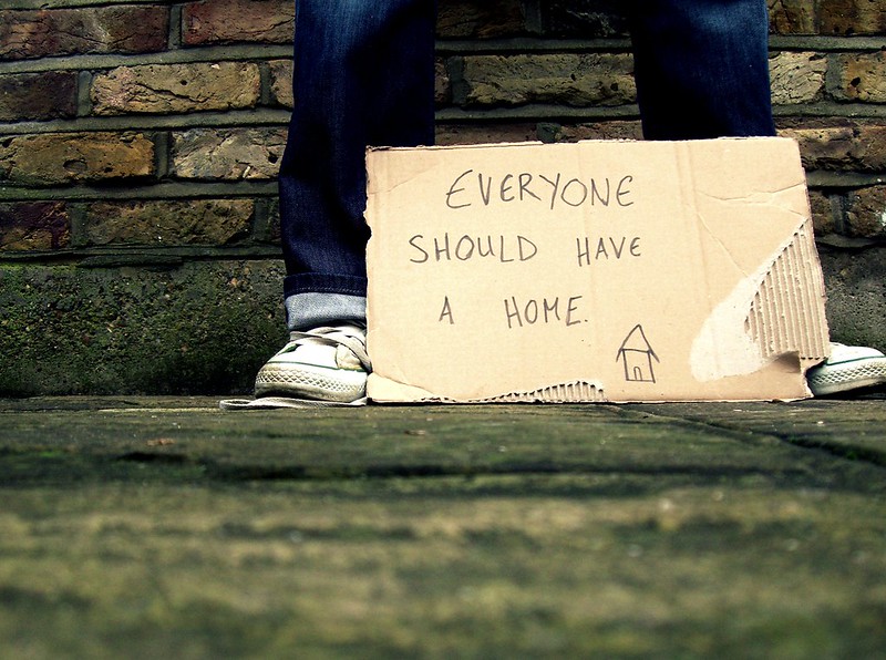 A sign by someones feet reads: 'Everyone should have a home'